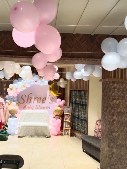 A wide view of a hall decorated for a baby shower. In addition to the main stage backdrop, we also decorated the ceiling with floating balloon bunches.