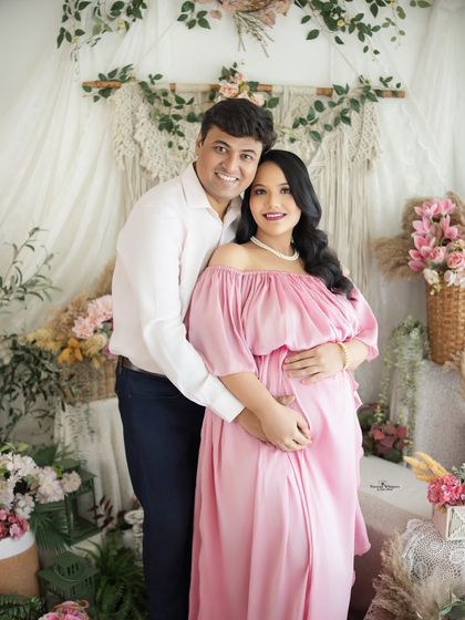 A happy couple's portrait, both smiling at the camera. Their joy is palpable in this shot from their pink-themed boho maternity session.