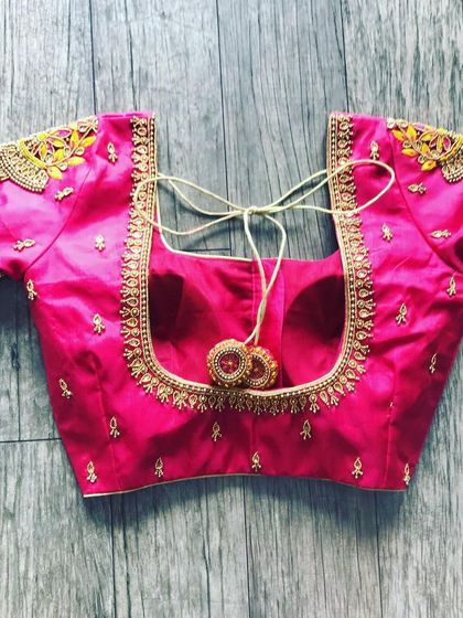 A pink blouse with minimal gold embroidery. The design is focused on the shoulders and neckline, with matching latkans.