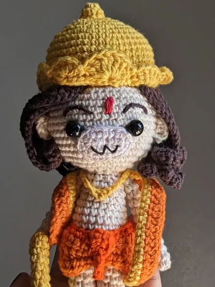 A close-up of the Lord Hanuman doll's face, showing his monkey-like features and kind eyes.