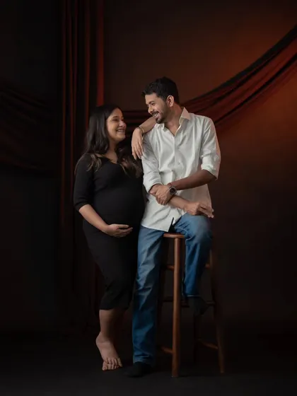 A stylish and classic couple's portrait against a dark, dramatic backdrop. Their interaction is natural and full of affection, creating a timeless memory.