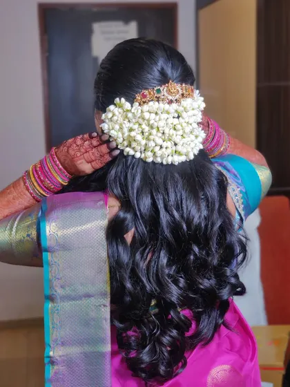 Another angle of the beautiful hairstyle, showing how the curls cascade down from the bun. This is a popular choice for South Indian brides.