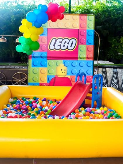 A large, inflatable ball pit with a slide, perfect for younger guests at this LEGO-themed party.