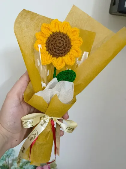 A single crochet sunflower, held in hand to show its size. It's a substantial, beautifully crafted flower that makes a lovely decorative piece.