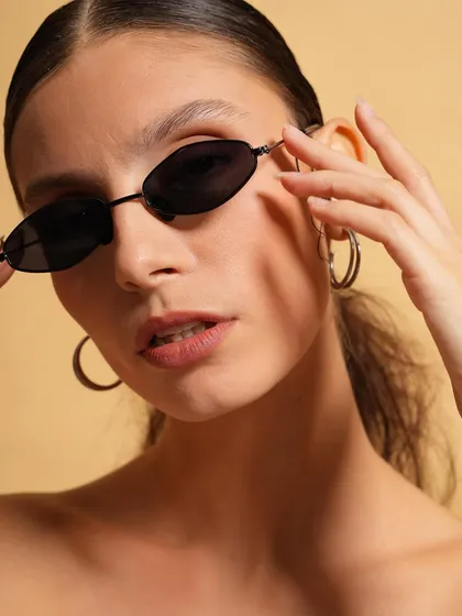 A confident pose from the same beauty shoot, with the model adjusting her sleek sunglasses. This shot has a cool, editorial feel, perfect for a fashion magazine or a stylish eyewear brand.