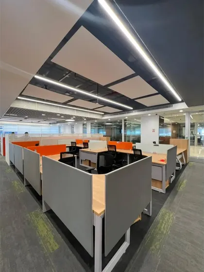 A view of the workstation cubicles with orange accent panels. The angular arrangement of the partitions breaks the monotony of a typical grid layout, adding a dynamic quality to the workspace.