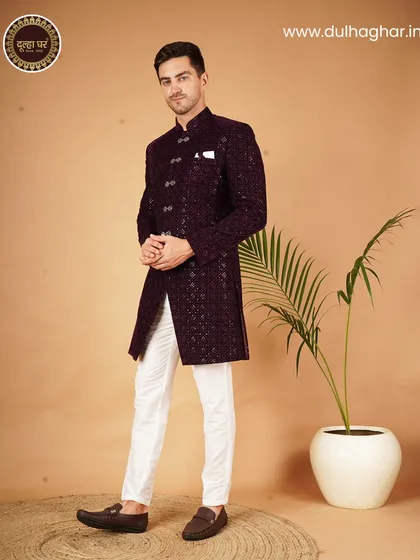 An Indo-Western sherwani in a deep purple hue, paired with crisp white trousers for a sharp, contemporary contrast. The intricate pattern and unique buttons make it a standout piece.
