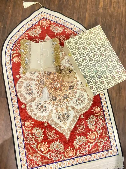 A beautiful Ramadan gift set featuring a dome-shaped prayer mat with an intricate red and white design. The set includes a custom Quran holder and a crystal tasbeeh, making it a perfect gift for the holy month.