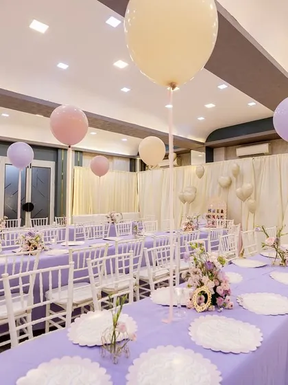 The elegant adult dining area at the princess-themed party, with long tables covered in lavender tablecloths and floating pastel balloons overhead.