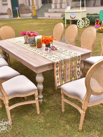Elegant wooden dining tables set for the fiesta, with patterned runners and simple cactus centerpieces.