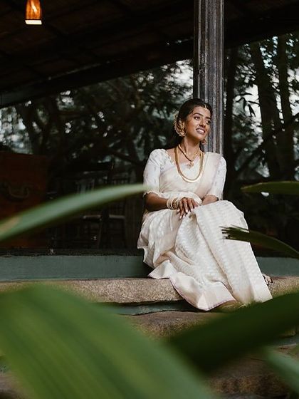 A bride sits on the steps, framed by green leaves, enjoying the peaceful ambiance of our venue.