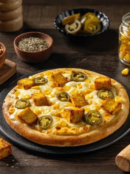 A paneer tikka pizza with corn and jalapenos, showcasing a popular Indian-fusion topping.