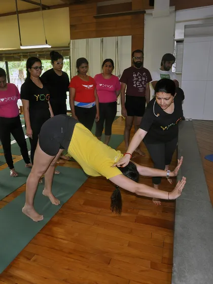 This image shows me providing a hands on correction for Adho Mukha Svanasana (Downward Facing Dog), a key pose we perfect in our beginner classes to build a strong foundation.