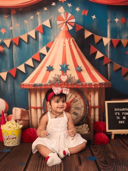 A sweet, seated portrait amidst the carnival fun. The detailed backdrop and props create a rich, storybook feel for these first birthday pictures.