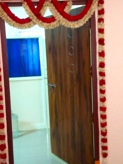 A simple home door flower decoration for a housewarming. The door is framed with garlands of red and white flowers for a classic look.