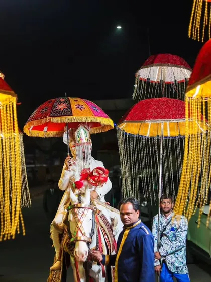 A grand, wide shot of the groom's baraat procession at night. The illuminated umbrellas and festive atmosphere are captured beautifully.