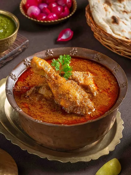 A vibrant Chicken Korma for The Mughal House. The styling with fresh herbs and spices in traditional serveware emphasizes its rich heritage.