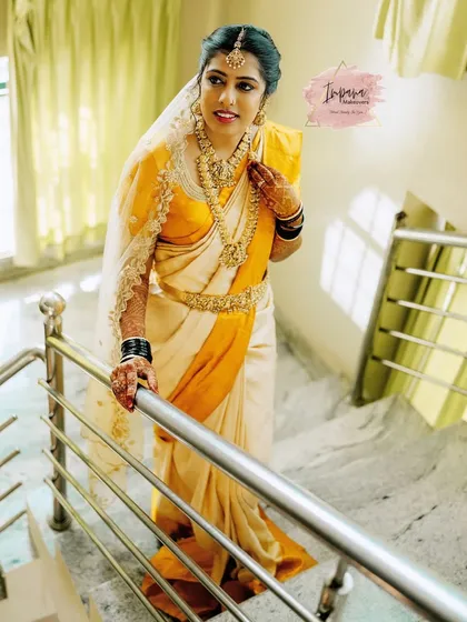 The epitome of grace. This bride looks serene and beautiful in her cream and yellow silk saree for her Muhurtham. Her makeup is kept soft and natural to highlight her features, paired with traditional gold jewellery.