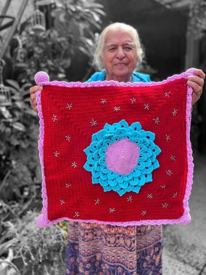 A vibrant red cushion cover with a stunning 3D floral applique in the center. This is a true statement piece that showcases intricate crochet work.