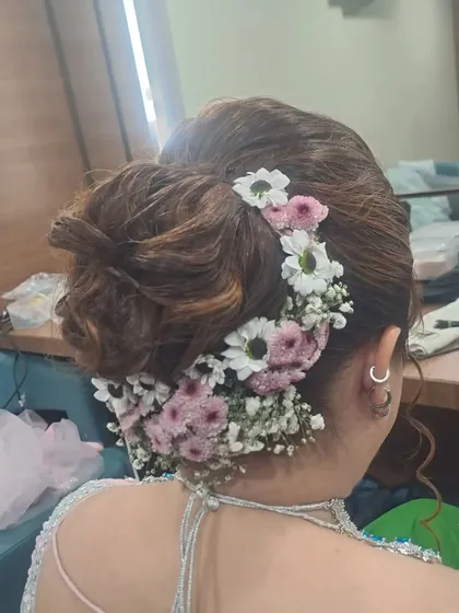 A detailed shot of a messy floral bun from the back. I use a combination of fresh daisies and baby's breath to create a beautiful, textured look that is perfect for a modern bride.