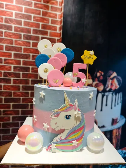 A magical unicorn cake with a pastel rainbow theme, decorated with edible stars and balloon lollipops.