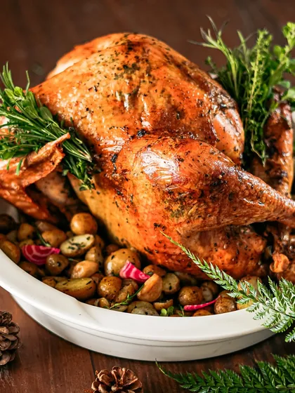 Our roasted turkey, garnished with an abundance of fresh rosemary and served on a bed of roasted baby potatoes. A complete and impressive main course for any holiday table.
