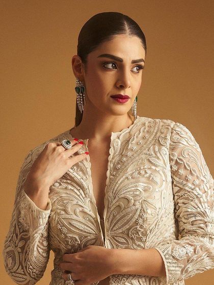 A close-up of the client, her bold red lip and emerald jewelry creating a powerful look.