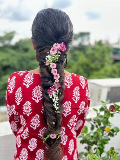 A beautiful fishtail braid adorned with a delicate trail of pink and white flowers, creating a whimsical and romantic look.