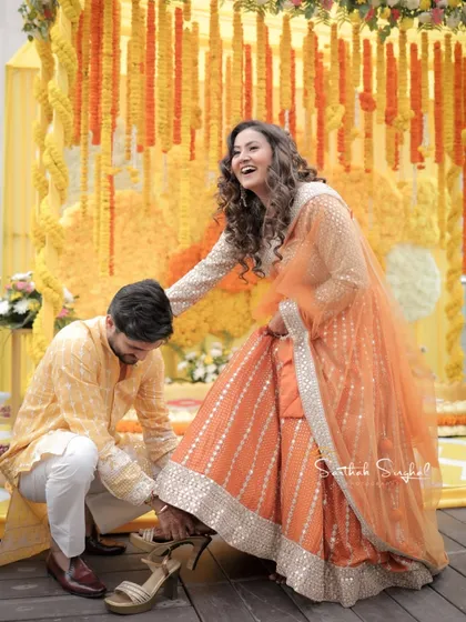 A sweet moment between the couple during their Haldi ceremony, with the groom helping the bride with her shoe.