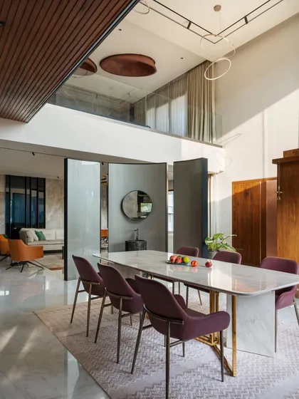 The double-height dining area is a centerpiece of the home, featuring pivoting partitions that can open or close the space. This flexibility allows for both intimate family dinners and larger social gatherings.