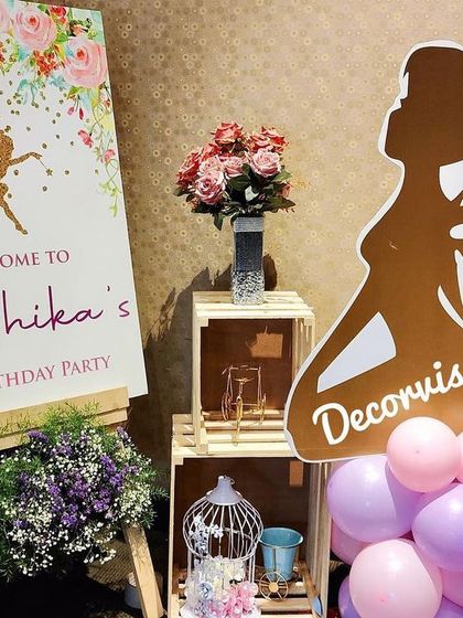 We create a warm welcome for your guests with a beautifully arranged entrance display. This setup for Mishika's party includes a custom welcome easel, floral arrangements, and decorative props like a birdcage and wooden crates.