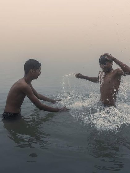 Two boys splash and play in the Ganga river in Bihar during the early morning, a candid shot full of energy and the simple joys of childhood.