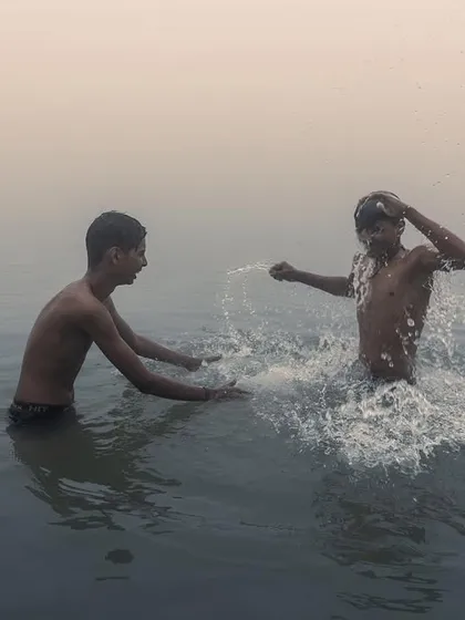 Two boys splash and play in the Ganga river in Bihar during the early morning, a candid shot full of energy and the simple joys of childhood.