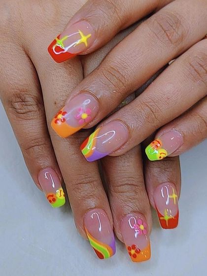 A bright and funky 70s-inspired design on square nails, featuring a rainbow of colors, flowers, and starbursts.