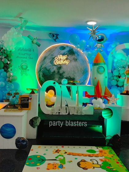 The space theme setup under green lighting, giving it an alien planet feel. The details include a large moon, satellites, and an astronaut prop.