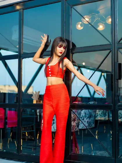A playful pose from the same red-themed shoot, showing how the makeup and styling work together for a confident and modern fashion statement.