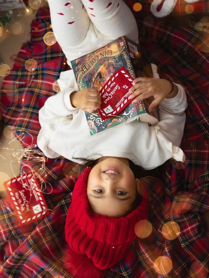 Dreaming of Christmas morning. This overhead shot on a plaid blanket, surrounded by books and letters to Santa, tells a story of holiday anticipation.