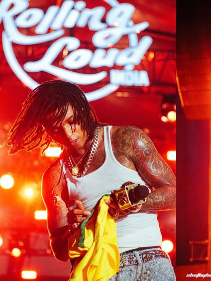 Swae Lee on stage at Rolling Loud India, with the festival branding lit up in red behind him.