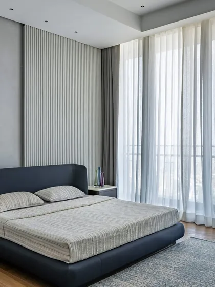 A minimalist bedroom with large windows that let in ample natural light. The simple color scheme and uncluttered design create a peaceful and airy retreat.