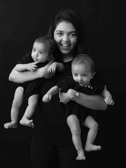 A super-mom in action! This photo captures the joy and energy of a mother holding her two twin babies, her smile says it all.