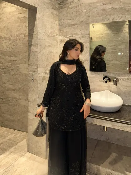 A candid-style shot in a modern, elegant bathroom, highlighting a black ethnic party wear outfit. This shows how the outfit looks in a realistic event setting.