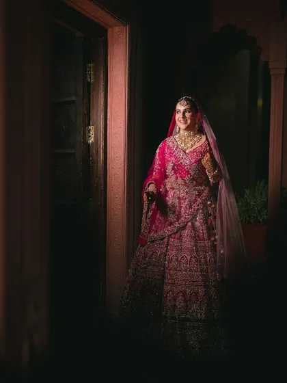 A stunning, dramatic portrait of the bride in her pink lehenga, looking like royalty.