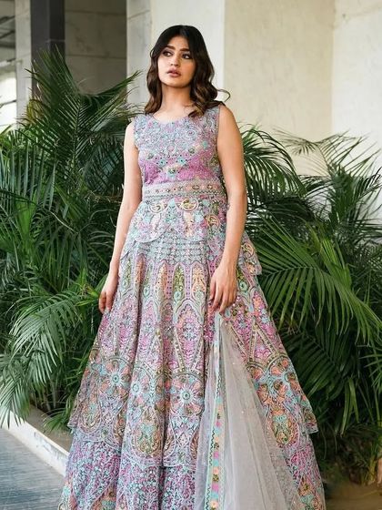 A model wearing a unique multi-colored pastel lehenga with a peplum-style top. This is a modern take on the traditional lehenga.