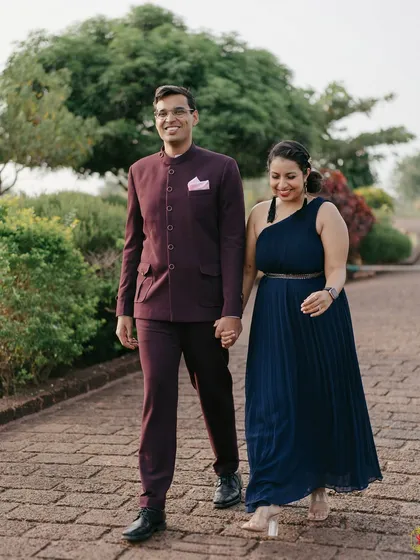 A candid shot of a couple walking hand-in-hand down a paved path, capturing a natural and happy moment.