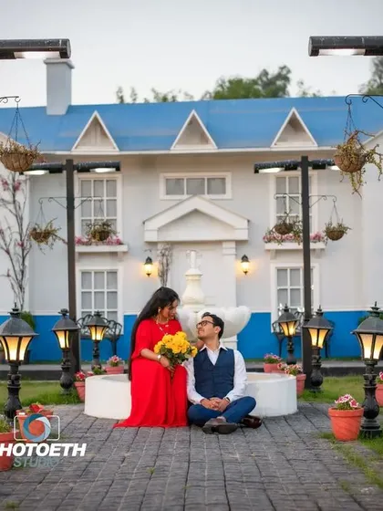 A sweet and romantic moment captured at the same lovely location. The groom sits at the bride's feet, creating a tender and intimate portrait.
