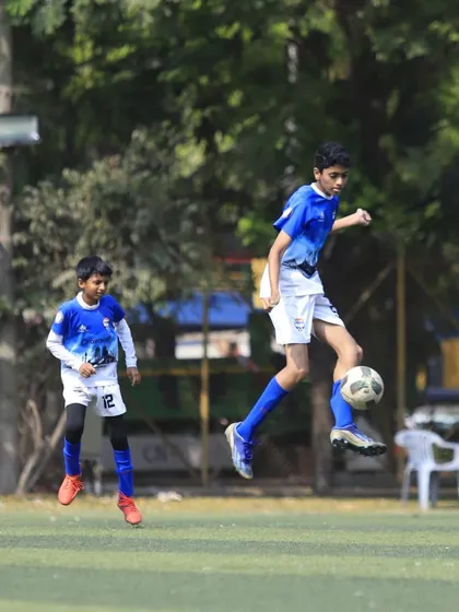 A player shows great technique, controlling the ball in mid-air during a U13 game.