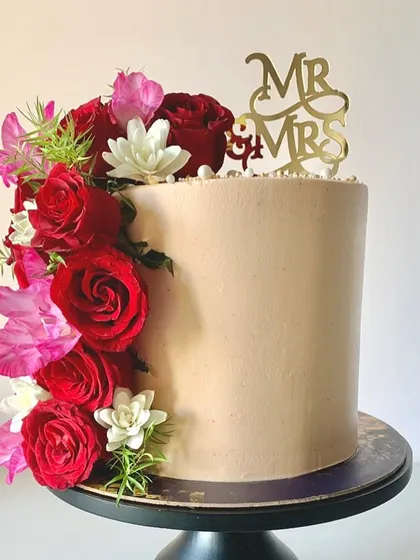 A memorable anniversary cake is something every couple deserves. This tall, single-tier cake is adorned with a cascade of fresh red and pink roses, creating a dramatic and romantic look.