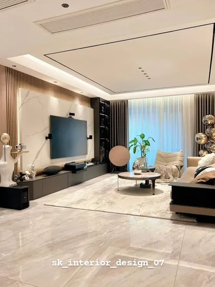 A minimalist and spacious living room with a large-format tile floor and a sleek, low TV console. The recessed ceiling lighting provides a clean and unobtrusive look.