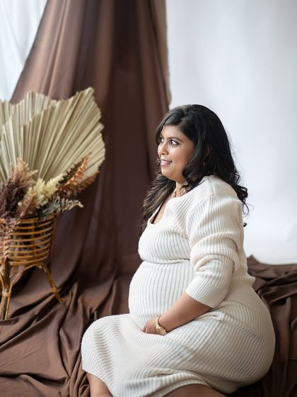 A serene solo portrait of the mother-to-be, bathed in soft light against our warm, bohemian-inspired studio backdrop.