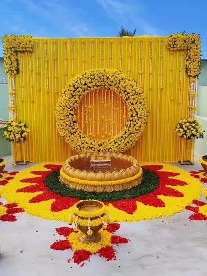 We transformed this terrace into a beautiful Haldi venue. The decor features a traditional yellow backdrop and an intricate flower rangoli on the floor, showing how we can utilize any space for your home wedding functions.